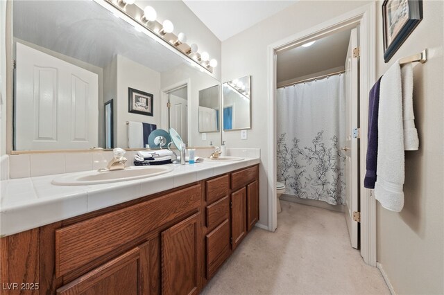 bathroom with a sink, toilet, and double vanity