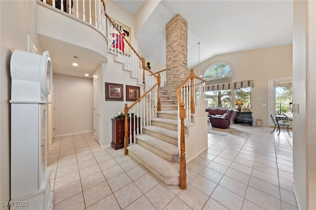 foyer entrance with high vaulted ceiling, light tile patterned flooring, stairway, and baseboards