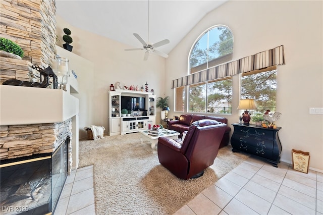 tiled living area featuring high vaulted ceiling, a ceiling fan, and a stone fireplace