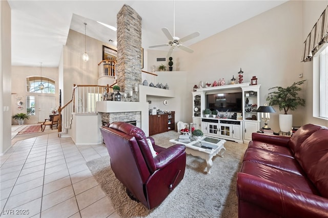 living room with tile patterned flooring, a stone fireplace, a high ceiling, and stairs