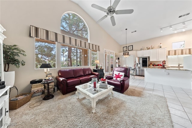 living area with light tile patterned floors, ceiling fan, high vaulted ceiling, and visible vents