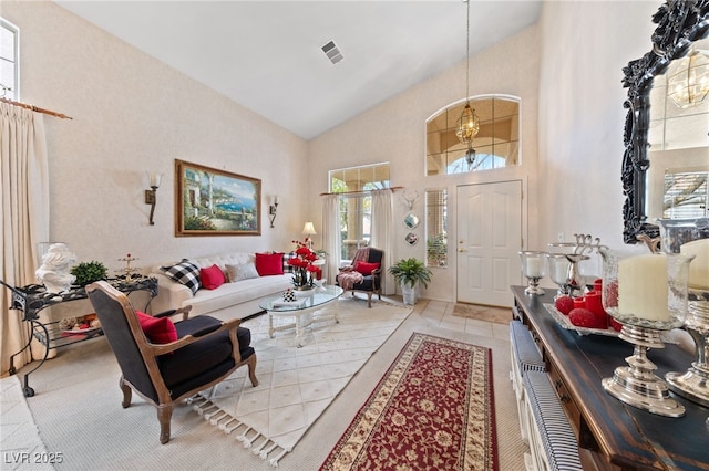 foyer entrance with high vaulted ceiling, visible vents, and an inviting chandelier