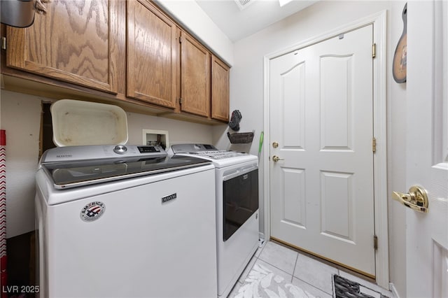 clothes washing area with cabinet space, light tile patterned floors, and separate washer and dryer