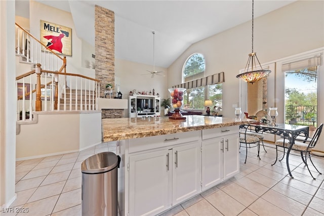 kitchen featuring a ceiling fan, hanging light fixtures, light stone countertops, white cabinetry, and light tile patterned flooring