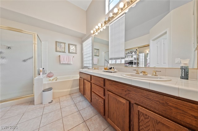 full bathroom featuring double vanity, a stall shower, a bath, tile patterned flooring, and a sink