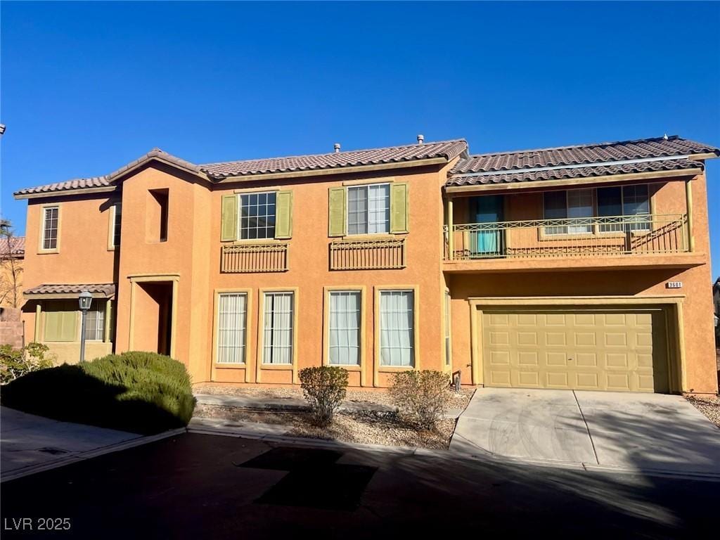 view of front of house with driveway, an attached garage, a tile roof, and stucco siding