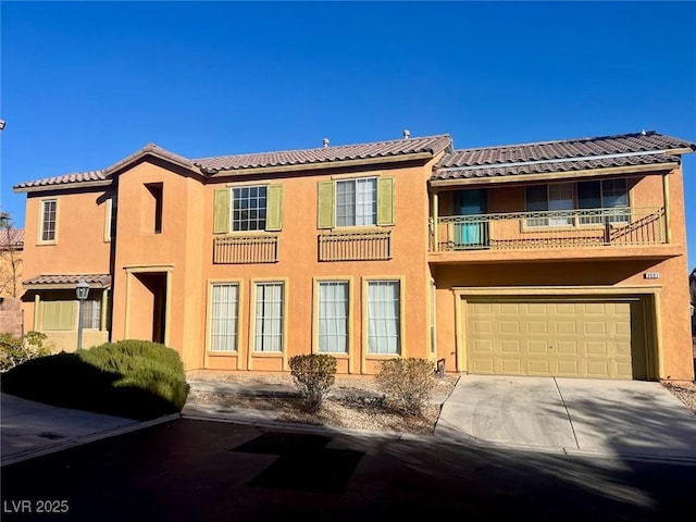 view of front of house with driveway, an attached garage, a tile roof, and stucco siding