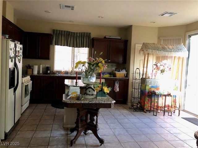 kitchen with a healthy amount of sunlight, white appliances, and visible vents