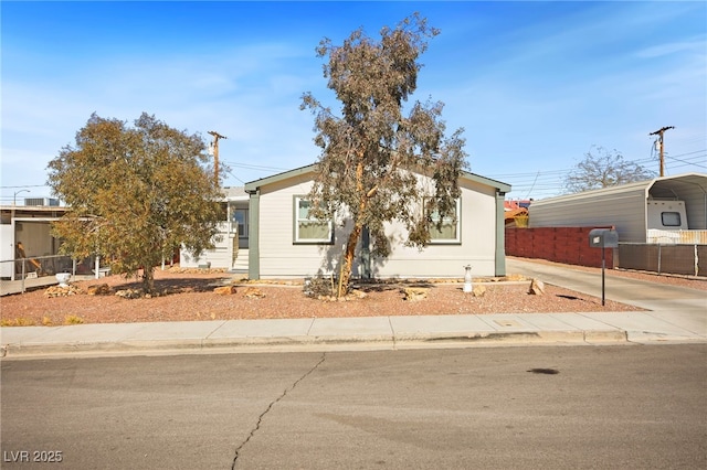 view of front of home with a detached carport, fence, and driveway