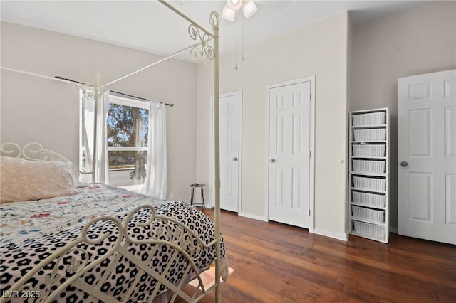 bedroom featuring multiple closets, ceiling fan, baseboards, and wood finished floors