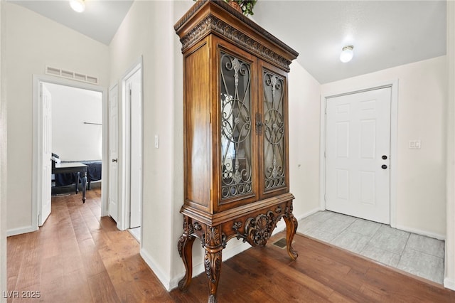 foyer featuring baseboards, visible vents, and light wood finished floors