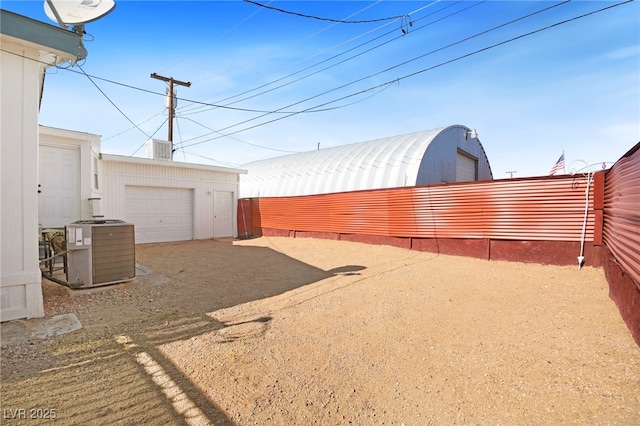 view of yard with an outbuilding, fence, a detached garage, and central air condition unit