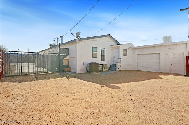 view of front of home featuring an attached garage, fence, dirt driveway, and central air condition unit