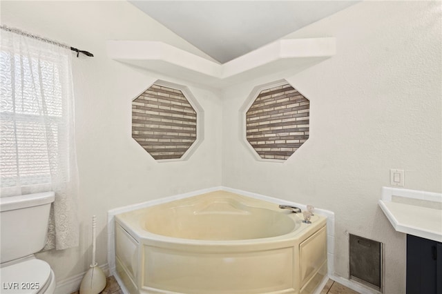 bathroom featuring toilet, a wealth of natural light, vaulted ceiling, and a bath