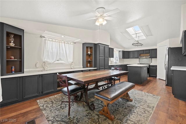 dining space with vaulted ceiling with skylight and wood-type flooring