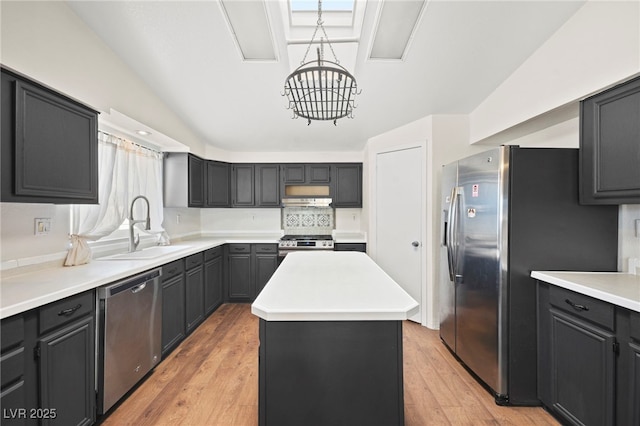 kitchen featuring light wood-style flooring, a kitchen island, appliances with stainless steel finishes, a chandelier, and a sink