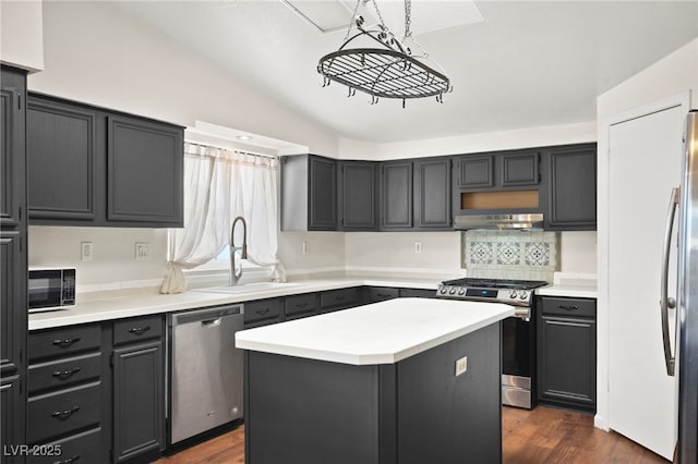 kitchen featuring stainless steel appliances, a sink, light countertops, and under cabinet range hood