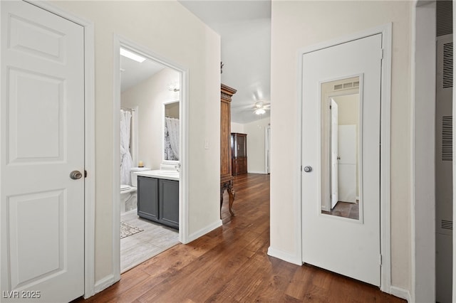 hall with baseboards, visible vents, and wood finished floors