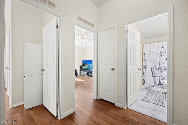 hall featuring dark wood-style floors, baseboards, and visible vents