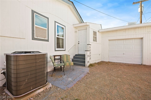 property entrance with a garage, dirt driveway, and central AC unit