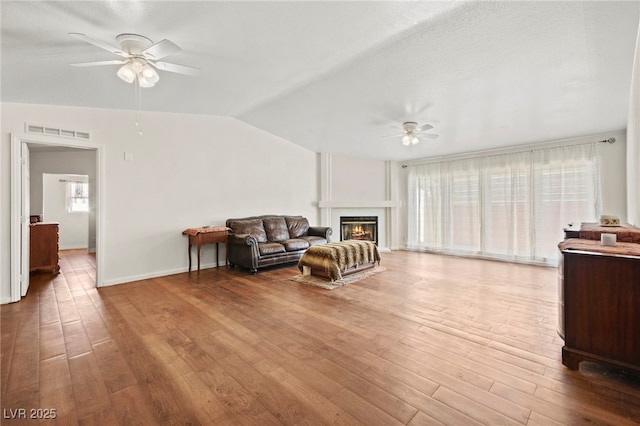 sitting room with ceiling fan, vaulted ceiling, wood finished floors, and visible vents