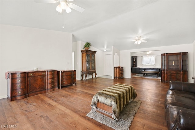 living area with a ceiling fan, lofted ceiling, and wood finished floors