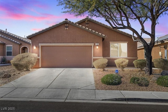 view of front of home featuring a tile roof, driveway, an attached garage, and stucco siding