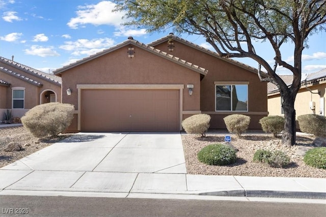 view of front of house with a garage, concrete driveway, a tile roof, and stucco siding