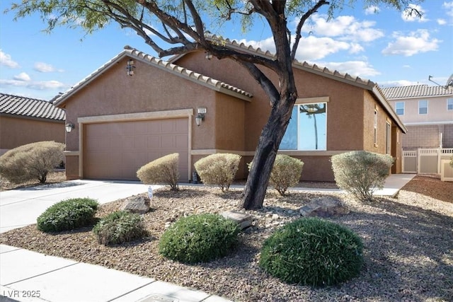 view of front of house featuring a tile roof, driveway, an attached garage, and stucco siding