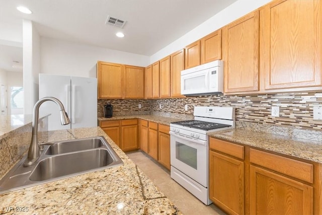 kitchen featuring tasteful backsplash, visible vents, light tile patterned flooring, a sink, and white appliances