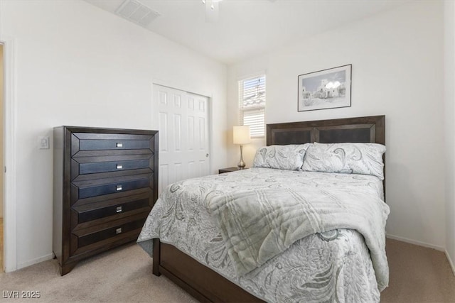 bedroom with baseboards, visible vents, a closet, and light colored carpet