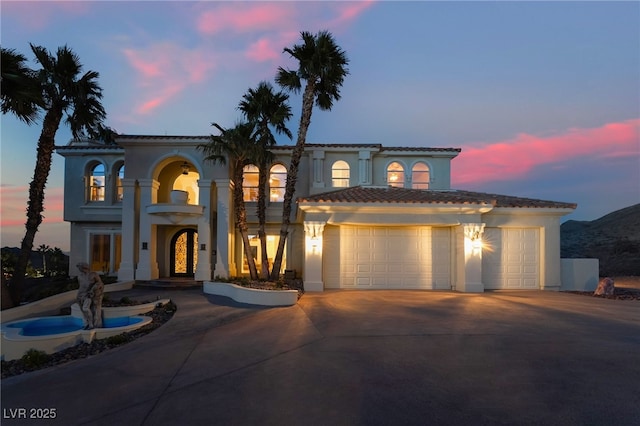 mediterranean / spanish home featuring concrete driveway, an attached garage, and stucco siding