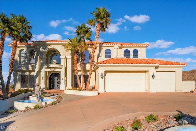 mediterranean / spanish-style home with a garage, a tile roof, concrete driveway, and stucco siding