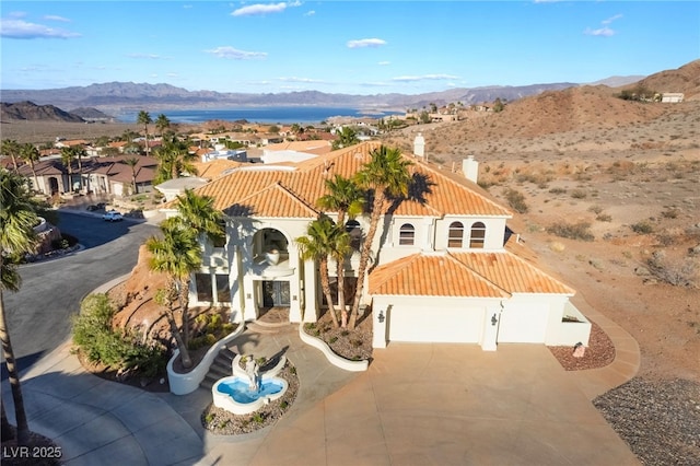 mediterranean / spanish-style home with a tile roof, a chimney, stucco siding, a mountain view, and driveway