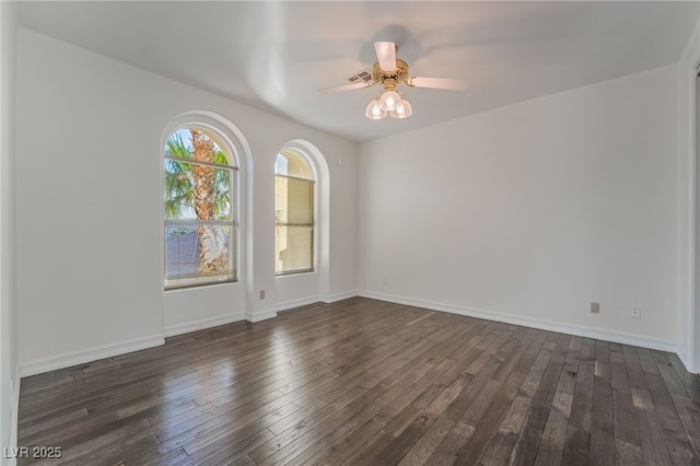 spare room featuring dark wood finished floors, a ceiling fan, and baseboards