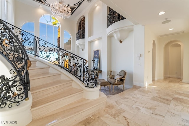 stairs featuring recessed lighting, a notable chandelier, a towering ceiling, baseboards, and marble finish floor