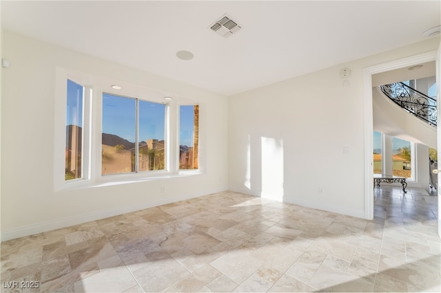 unfurnished room featuring a wealth of natural light, visible vents, stairway, and baseboards