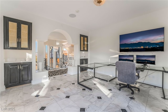 unfurnished office featuring arched walkways and marble finish floor