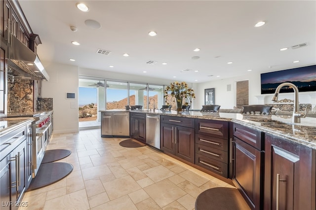 kitchen with stone counters, visible vents, stainless steel appliances, and a sink