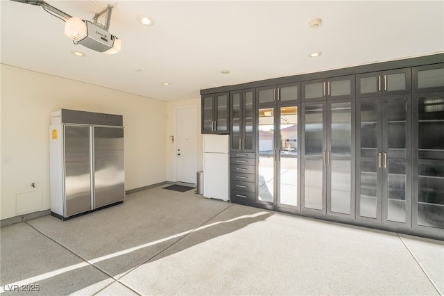 interior space with french doors, a garage door opener, recessed lighting, freestanding refrigerator, and built in refrigerator