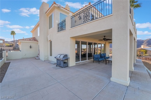 rear view of property with a ceiling fan, a patio, a balcony, a tile roof, and stucco siding