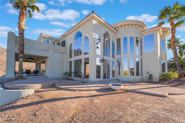 back of property with a tile roof, a patio, and stucco siding