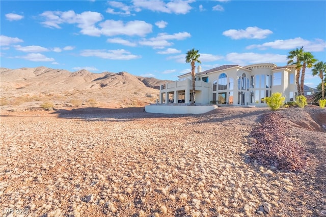 back of property featuring a balcony, a mountain view, and stucco siding