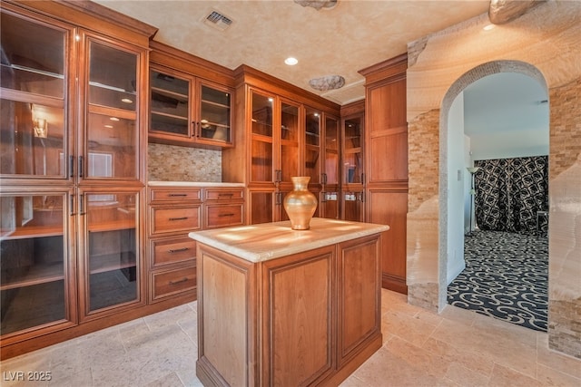 interior space with arched walkways, visible vents, and stone tile floors