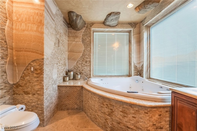 full bath with tile patterned floors, vanity, toilet, and a tub with jets