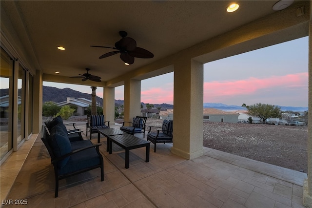 patio terrace at dusk with a mountain view, outdoor lounge area, and a ceiling fan