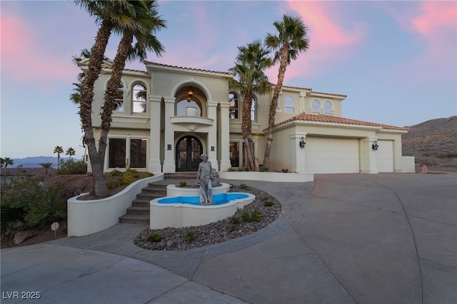 mediterranean / spanish-style home featuring french doors, stucco siding, a mountain view, a garage, and driveway