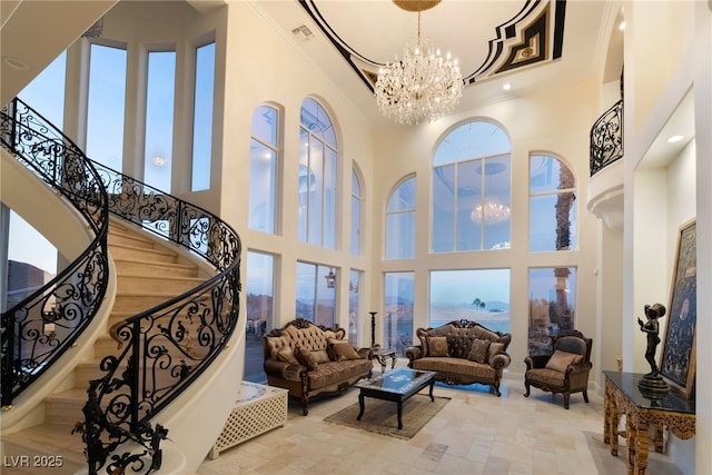 living area with a notable chandelier, a towering ceiling, visible vents, stairs, and ornamental molding