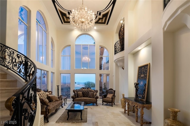 living area with ornamental molding, a notable chandelier, a high ceiling, and stairs