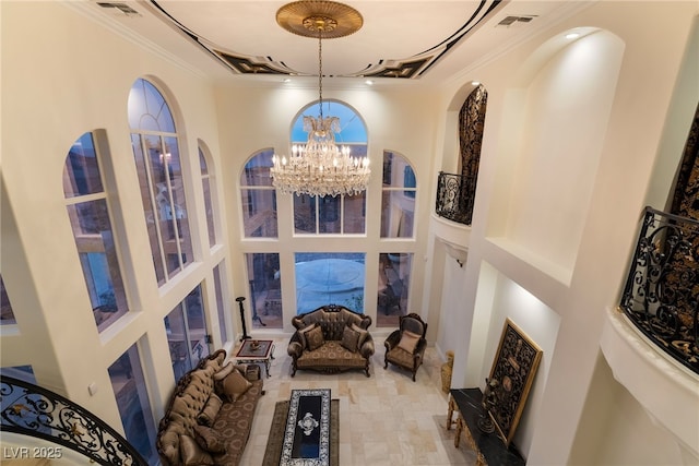 interior space with visible vents, crown molding, a towering ceiling, and an inviting chandelier